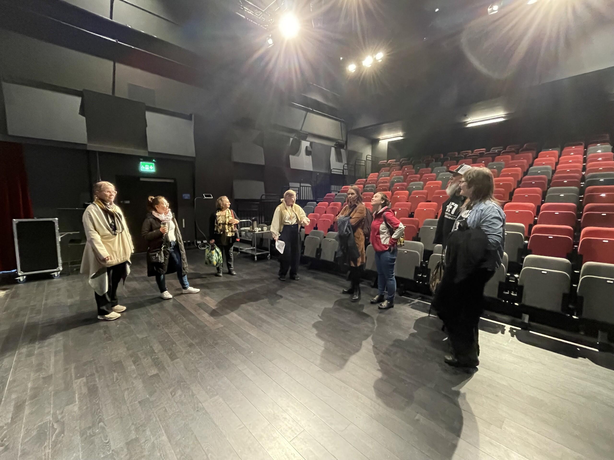 Kuvassa ryhmä opintomatkalaisia tutustuu kulttuuritalon teatteritiloihin ja toimintaan.